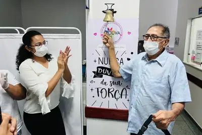 notícia: Com a família e amigos, radialista toca o sino que celebra fim do tratamento de quimioterapia na unidade oncológica do Governo do Amapá