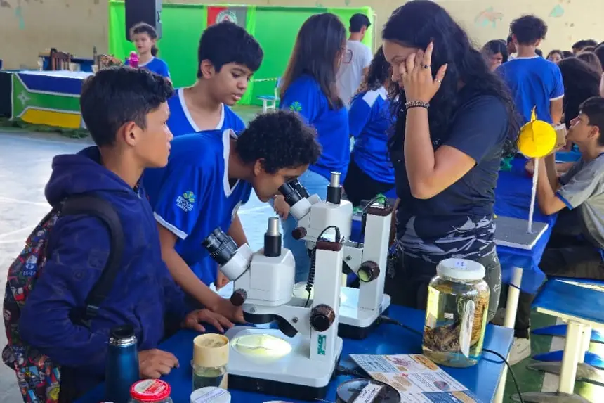 Alunos usando aparelho microscópio 