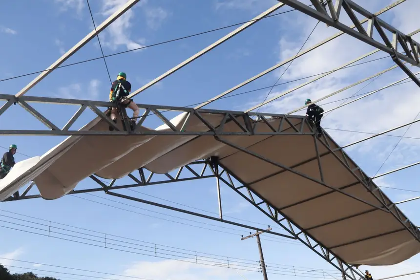 Trabalhadores montam a cobertura dos espaços usando lonas gigantes 