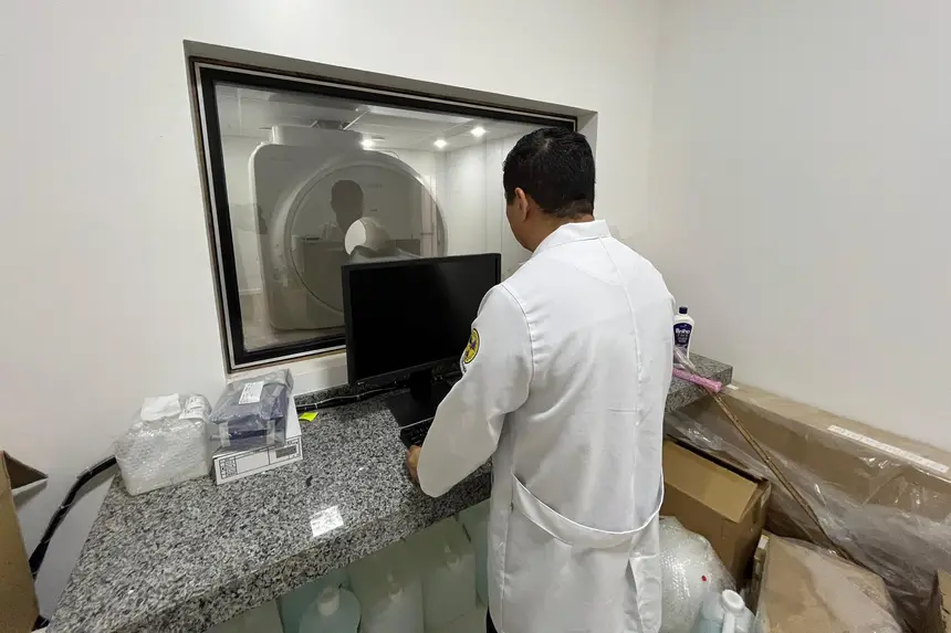 Profissional monitora a captação de imagens tridimensionais na sala de comando da tomografia